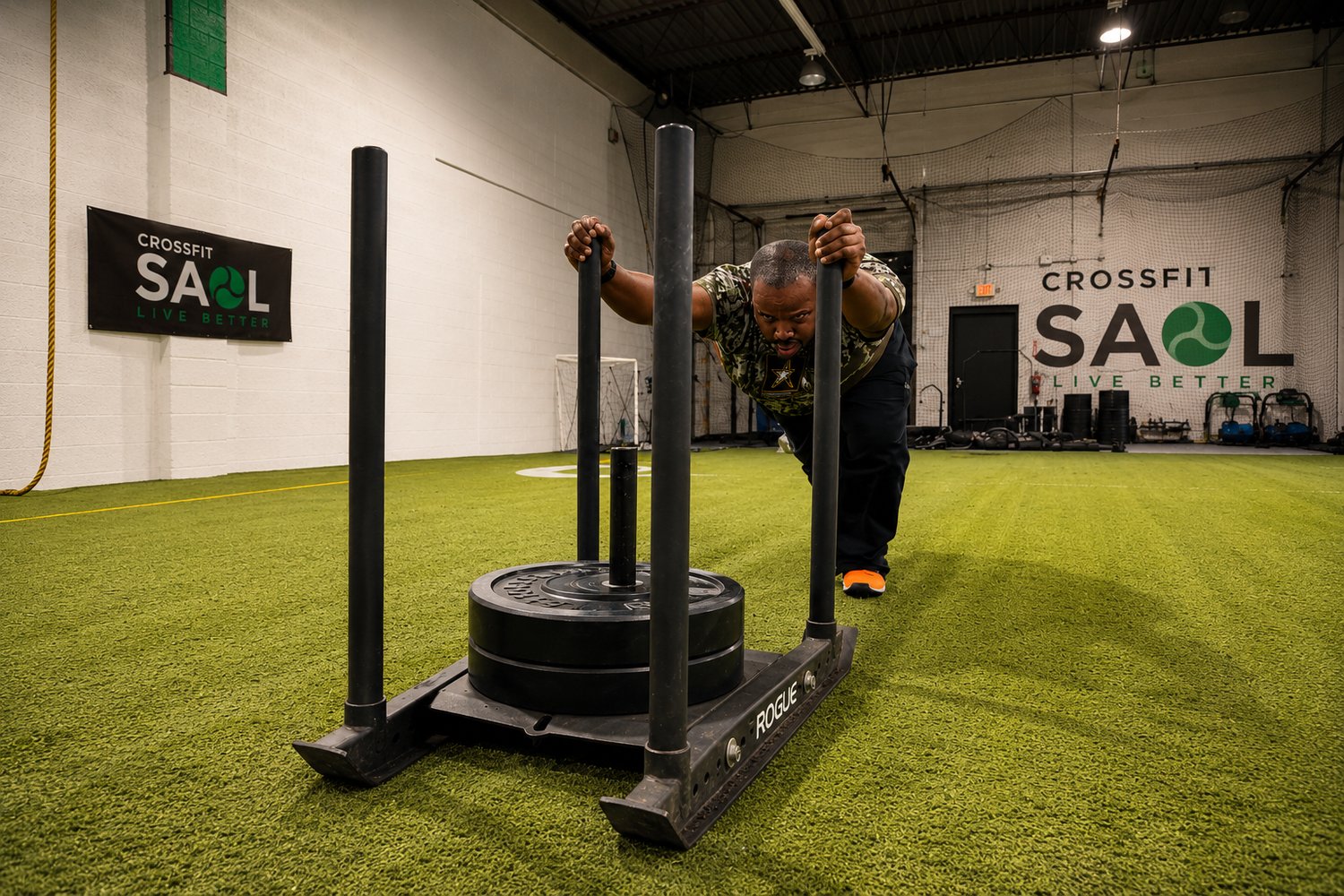 An athlete pushing a Rogue sled on the turf at CrossFit Saol